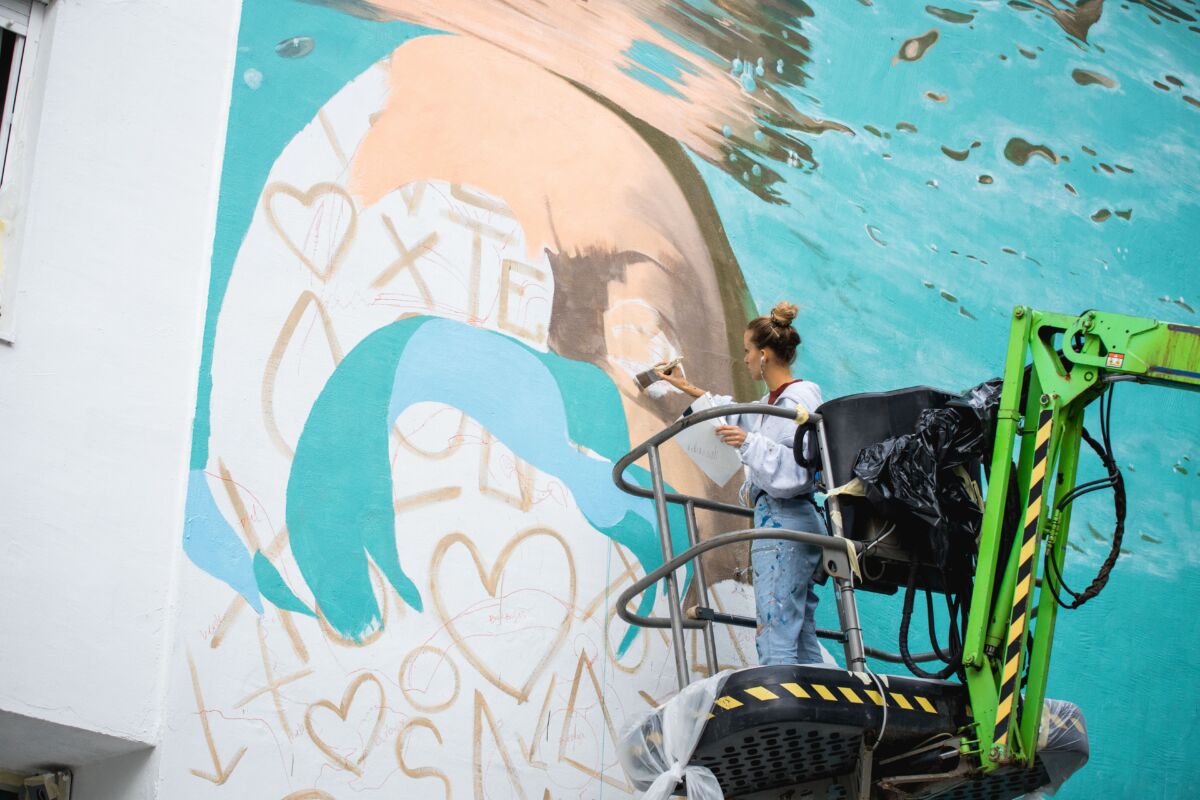 Street art umjetnica Mandioh tijekom izrade murala na FASADA Festivalu 2023, rad na velikoj fasadi u urbanom prostoru