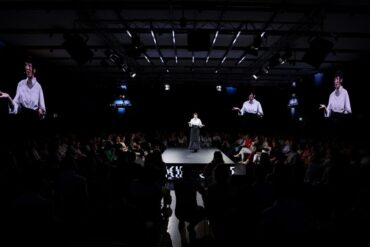 Govornica na dugačkoj catwalk pozornici okruženoj publikom s obje strane i četiri velika ekrana s njezinim likom, u tamnoj dvorani Dana komunikacija 2026.