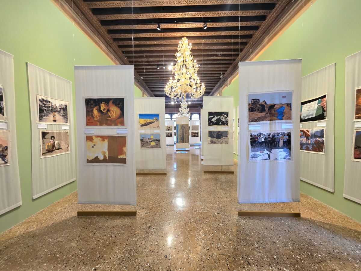 Centralni prolaz izložbe Gaza Genocide Tapestry, Palazzo Mora, Venecija 2026. — platneni nosači s panelima tatreez veza, Palestine Museum US.