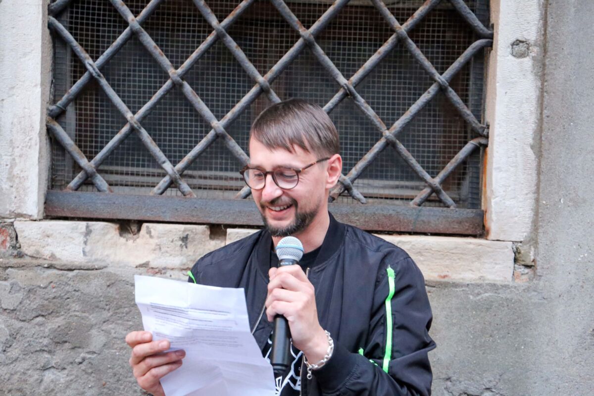 Mladen Bundalo čita govor s papira uz osmijeh, s mikrofonom u ruci, ispred kamenog zida Palazzo Malipiera, vernisaž izložbe Domus Diasporica, Paviljon BiH, Venecija, 8. maja 2026.