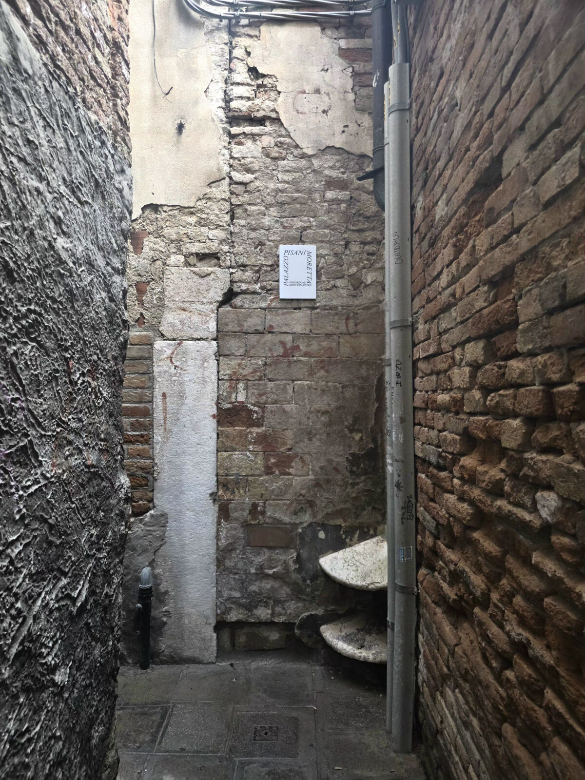 Uski prolaz s ulaznom tablom Fondazione Dries Van Noten, Palazzo Pisani Moretta Venecija 2026, foto FBL