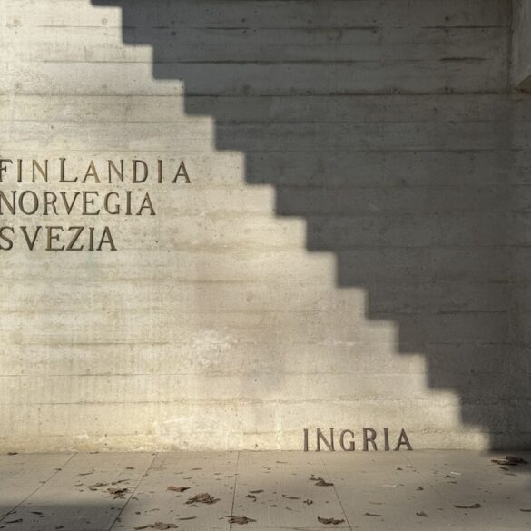 Vanjski betonski zid Nordijskog paviljona s natpisima Finlandia, Norvegia, Svezia u gornjem lijevom uglu i riječju INGRIA postavljenom pri dnu desno, dok geometrijska sjena stepenica dijeli zid na osvjetljeni i zatamnjeni dio.