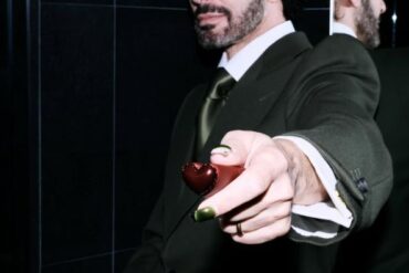 Marc Jacobs u tamnozelenom odijelu pruža maleno srce prema kameri, s odrazom u ogledalu u pozadini — fotografija s njegovog Instagram profila @themarcjacobs