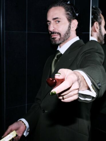 Marc Jacobs u tamnozelenom odijelu pruža maleno srce prema kameri, s odrazom u ogledalu u pozadini — fotografija s njegovog Instagram profila @themarcjacobs