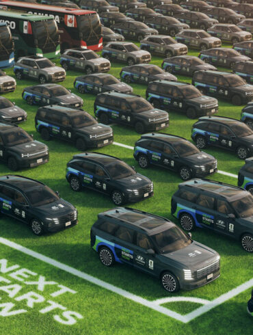 Stotine Hyundaijevih vozila s Next Starts Now natpisom na travnjaku uz autobuse i Spot robote