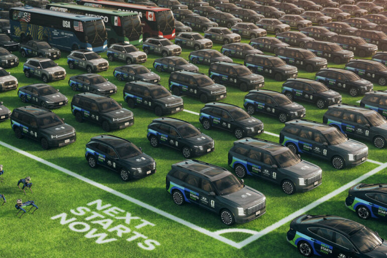 Stotine Hyundaijevih vozila s Next Starts Now natpisom na travnjaku uz autobuse i Spot robote