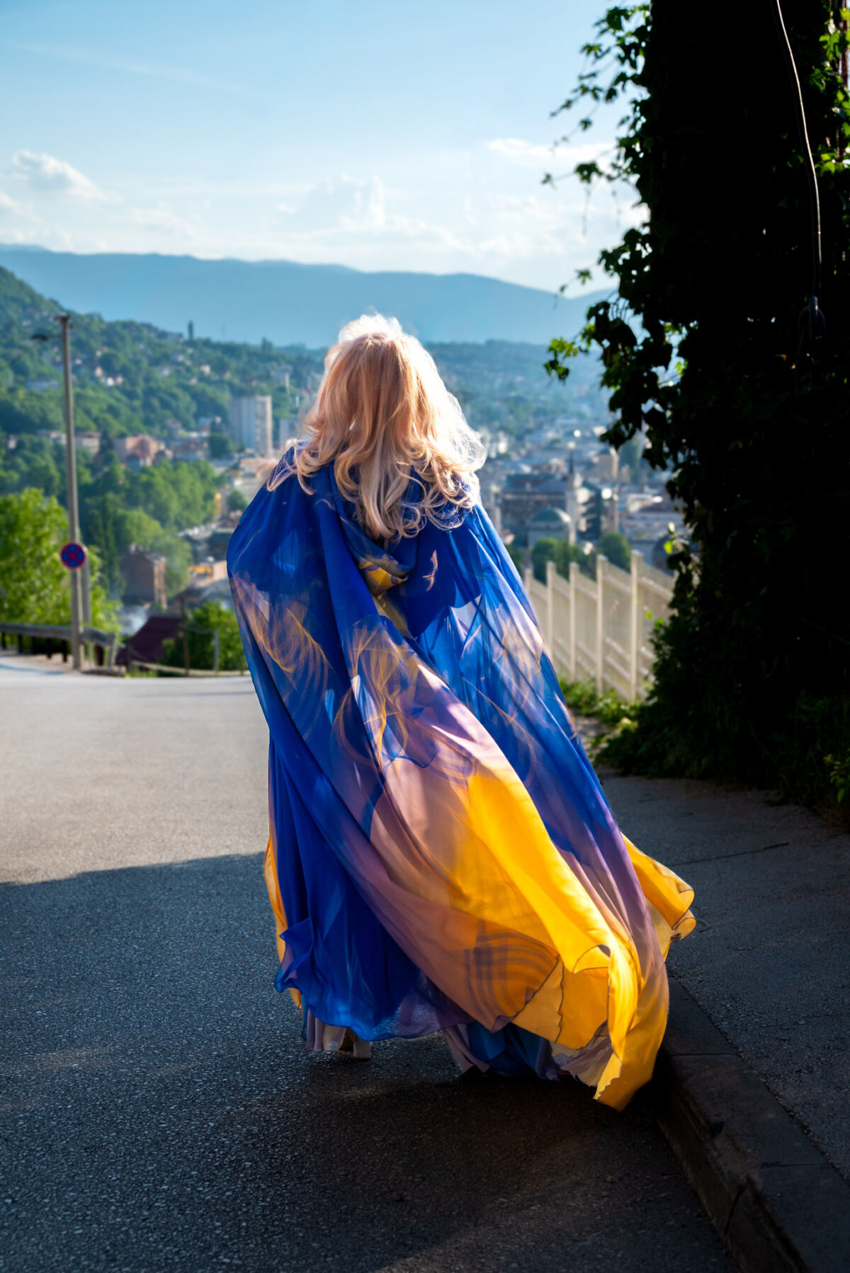 Model u plavo-žutom ogrtaču kolekcije Lilium Bosniacum Belme Tvico s panoramom Sarajeva u pozadini