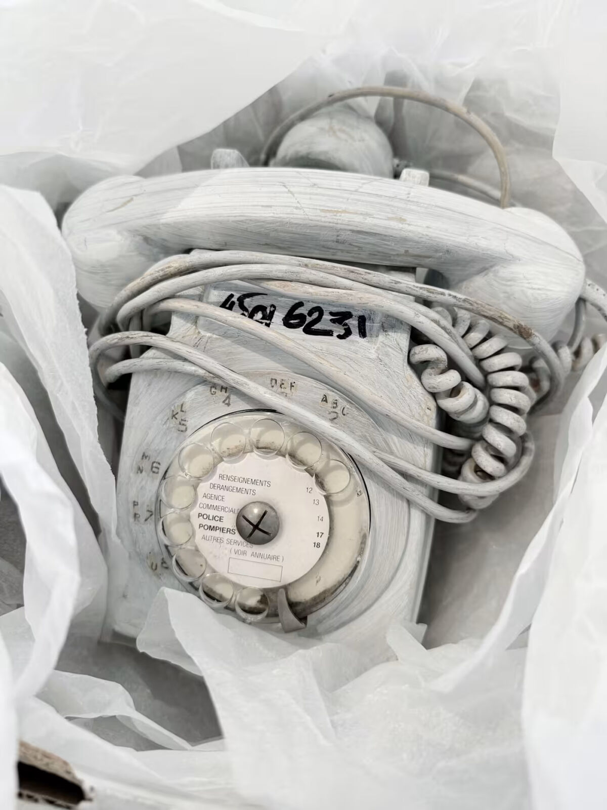 Bijelo okrečeni rotacijski telefon s Margieleovim telefonskim brojem ispisanim flomasterom, iz njegova ureda 1988. godine