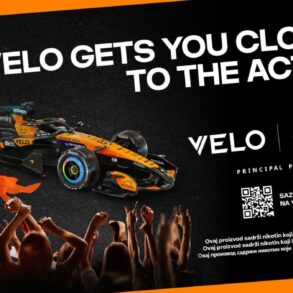 VELO nagradni konkurs – McLaren F1 bolid u narandžasto-crnim bojama s VELO logom, uz slogan "VELO Gets You Closer to the Action" i QR kod za učešće u nagradnom takmičenju za vikend u Monzi. Samo za 18+.