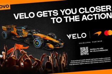 VELO nagradni konkurs – McLaren F1 bolid u narandžasto-crnim bojama s VELO logom, uz slogan "VELO Gets You Closer to the Action" i QR kod za učešće u nagradnom takmičenju za vikend u Monzi. Samo za 18+.