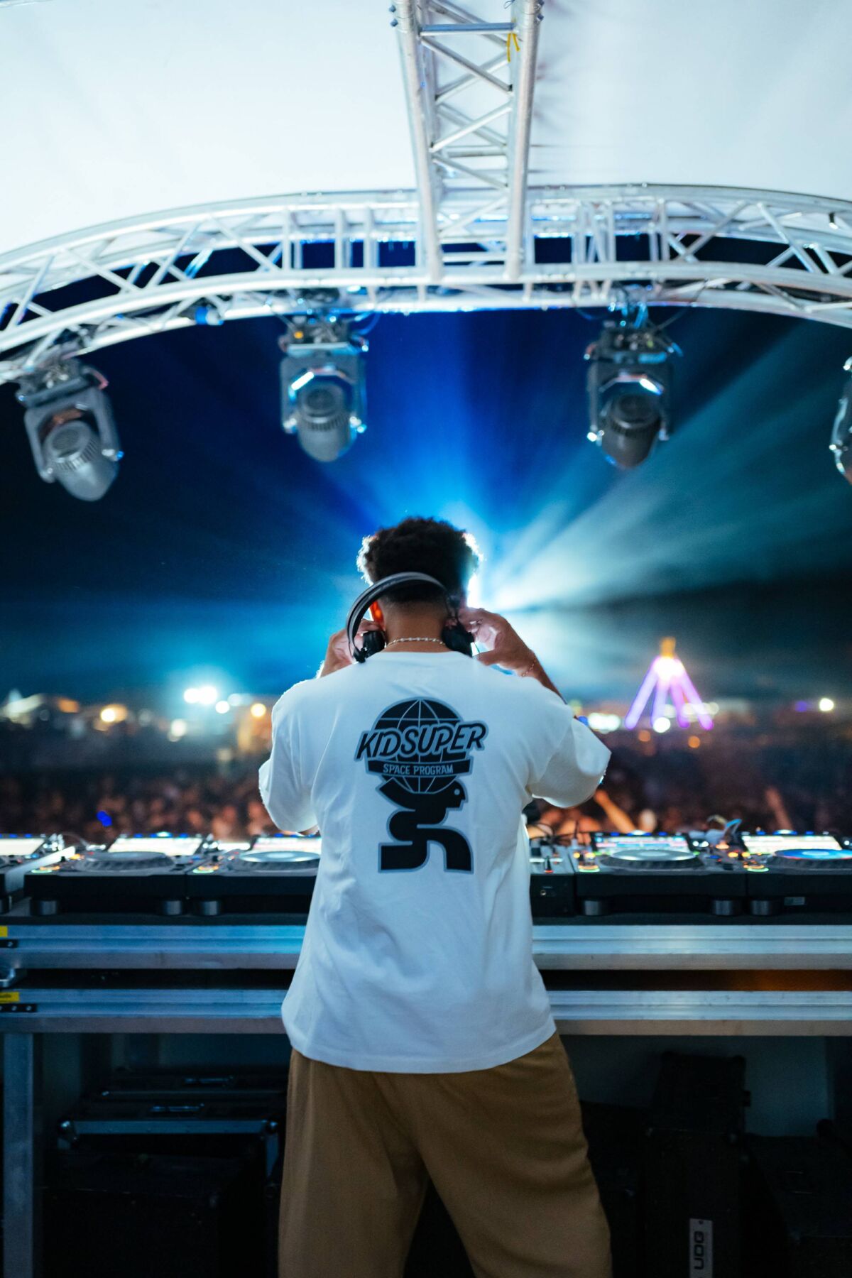 DJ u KidSuper majici stavlja slušalice na bini pred publikom na Velikoj plaži