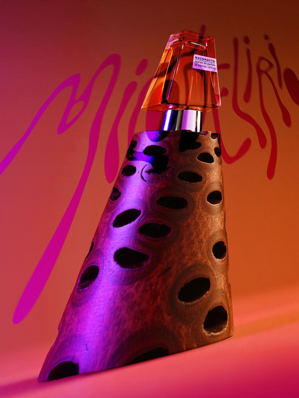 Nasomatto Micodelirio extrait de parfum 30ml bočica na drvenom postolju s rupama, roze grafiti natpis u pozadini