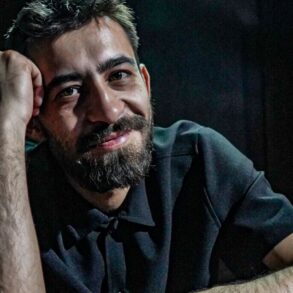 Irfan Ribić, osnivač i umjetnički direktor RAW SOUL THEATRE, naslonjen na sto u zatamnjenom prostoru teatra