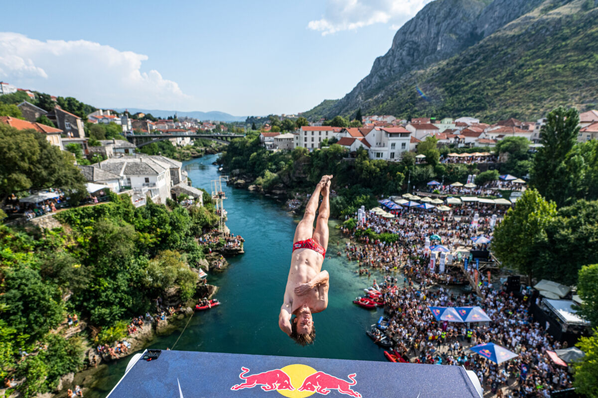 Skakač u salto poziciji naglavačke tokom skoka sa platforme Red Bull Cliff Diving iznad Neretve u Mostaru