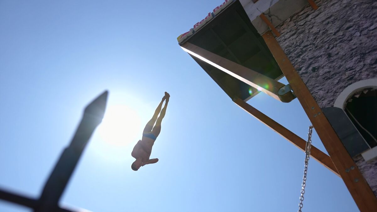Red Bull Cliff Diving skakač u skoku naglavačke sa platforme ispod Starog mosta u Mostaru, silueta na suncu