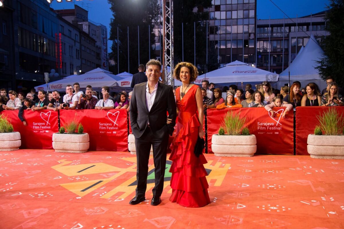 Danis Tanović u tamnom odijelu i supruga Maëlys de Rudder Tanović u crvenoj haljini s volanima poziraju na crvenom tepihu 25. Sarajevo Film Festivala 2019 - FBL Magazin