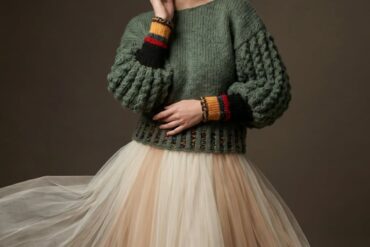 Model u ručno rađenom šarenom pletenom kaputu ispred betonskog zida, LeMu Studio by Mothershands