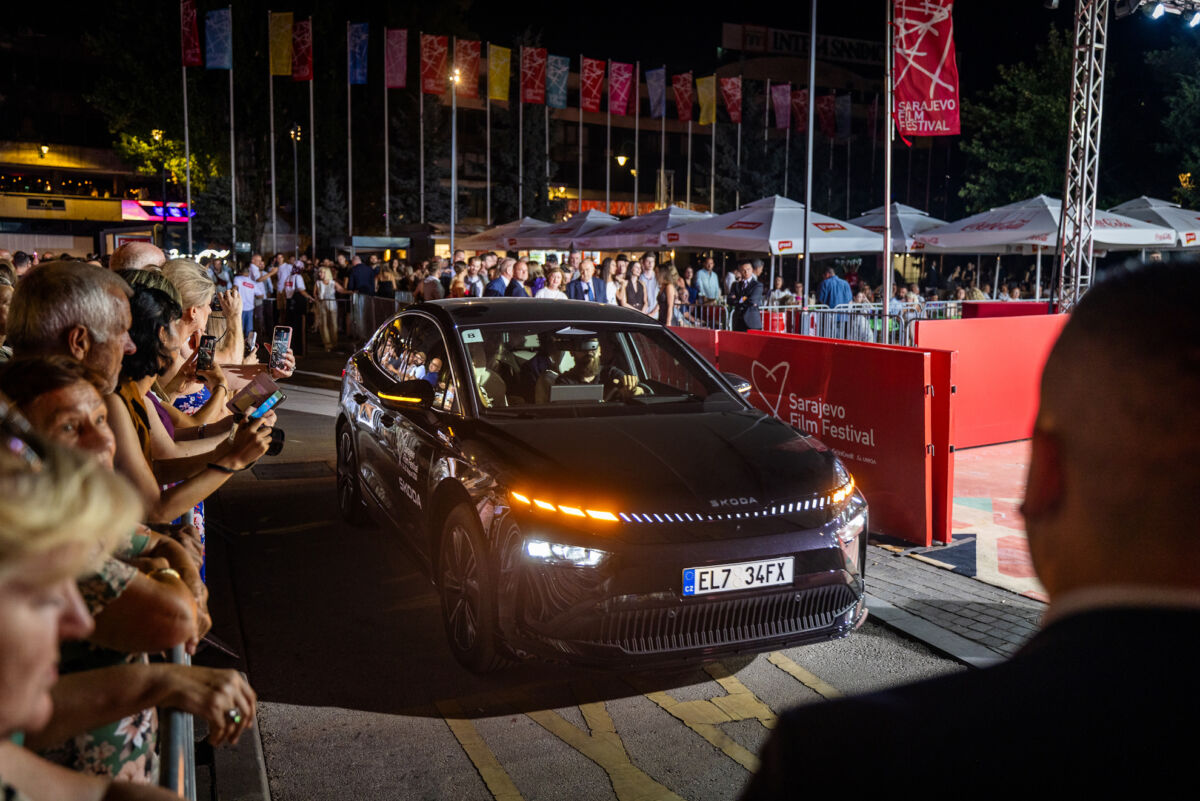 Električni Škoda Enyaq sa aktiviranim halo svetlima na crvenom tepihu Sarajevo Film Festivala, okružen publikom koja fotografiše vozilo