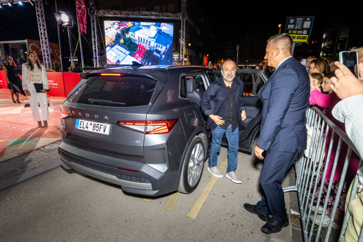 "Reditelj Asghar Farhadi izlazi iz Škoda Superba na festivalu; muškarac u tamnom odelu pomaže mu iz vozila nakon što je stigao na crveni tepih"