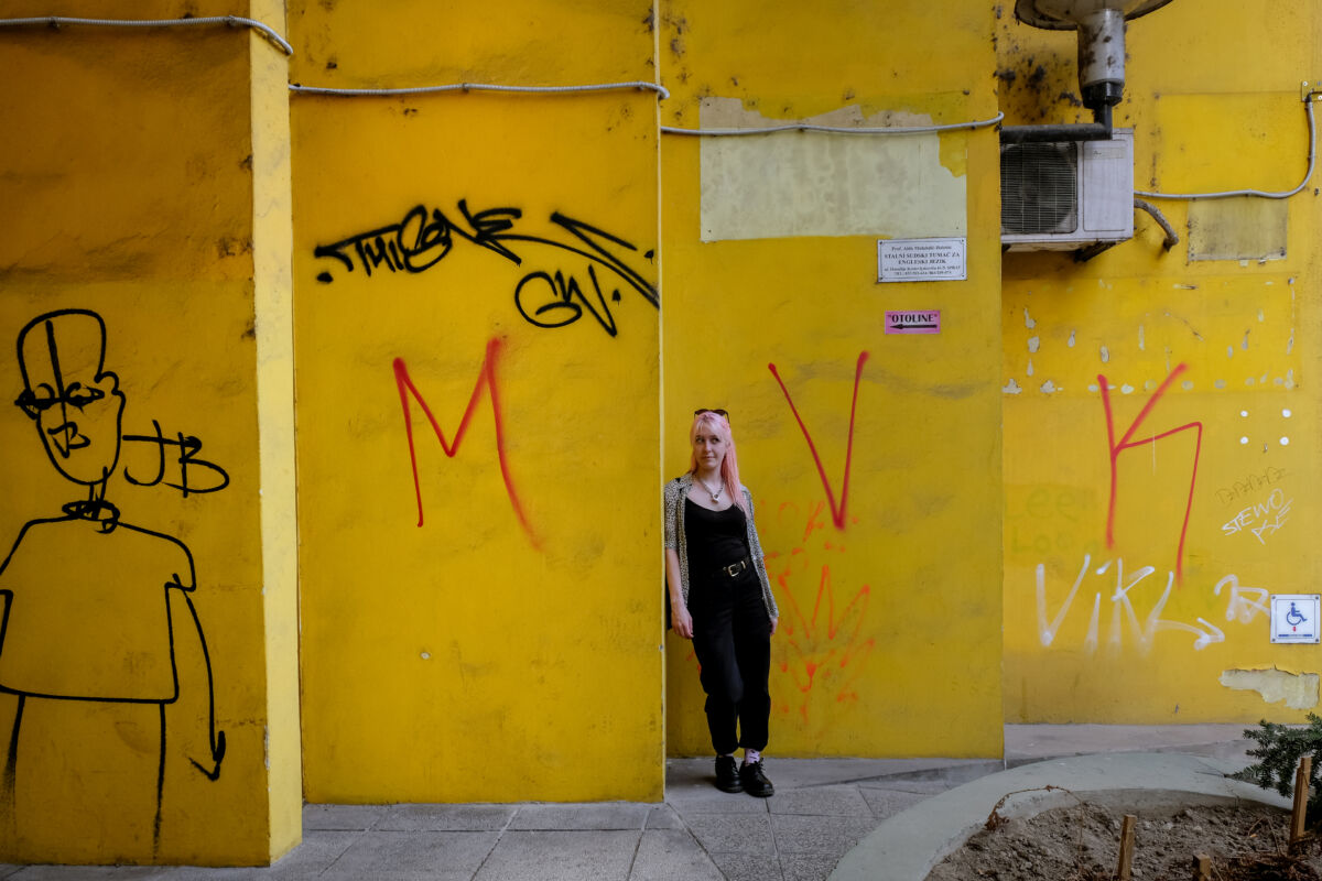 Ewa Anna Kumelowski ispred žutog zida s grafitima u Sarajevu