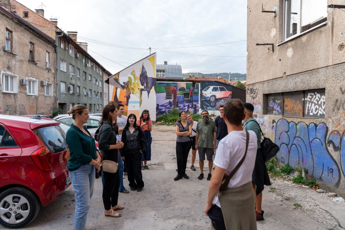 Grupa posjetilaca na street art turi ispred murala u Sarajevu tokom FASADA Festivala