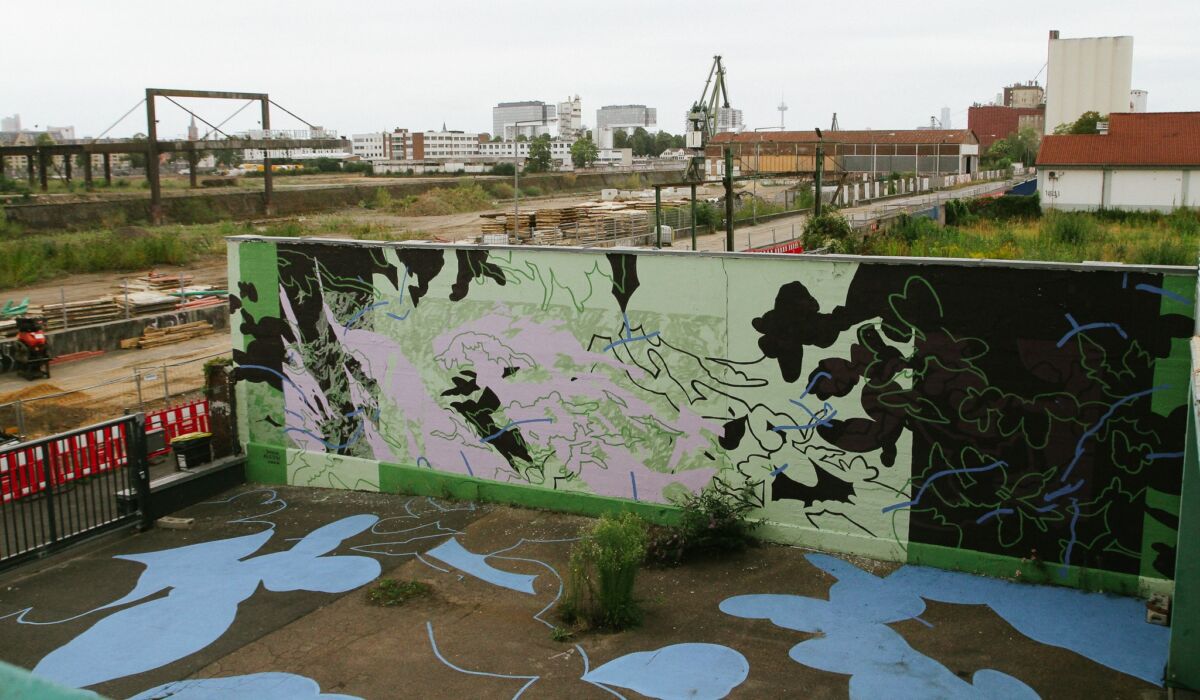 Mural Dane Alessi A esté verde, lo llaman Kölsche Brückengrün na otvorenom prostoru, s apstraktnim biljnim motivima u zelenoj, ljubičastoj i crnoj.
